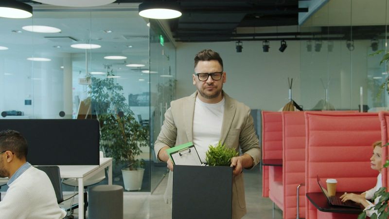 An employee carrying a box of belongings out of an office