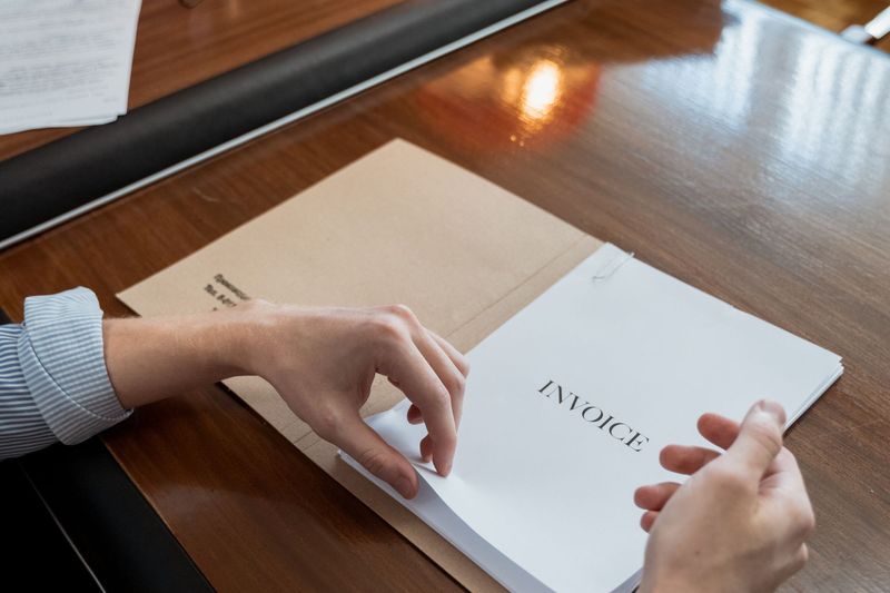 Hands sorting tax invoices on a wooden office desk